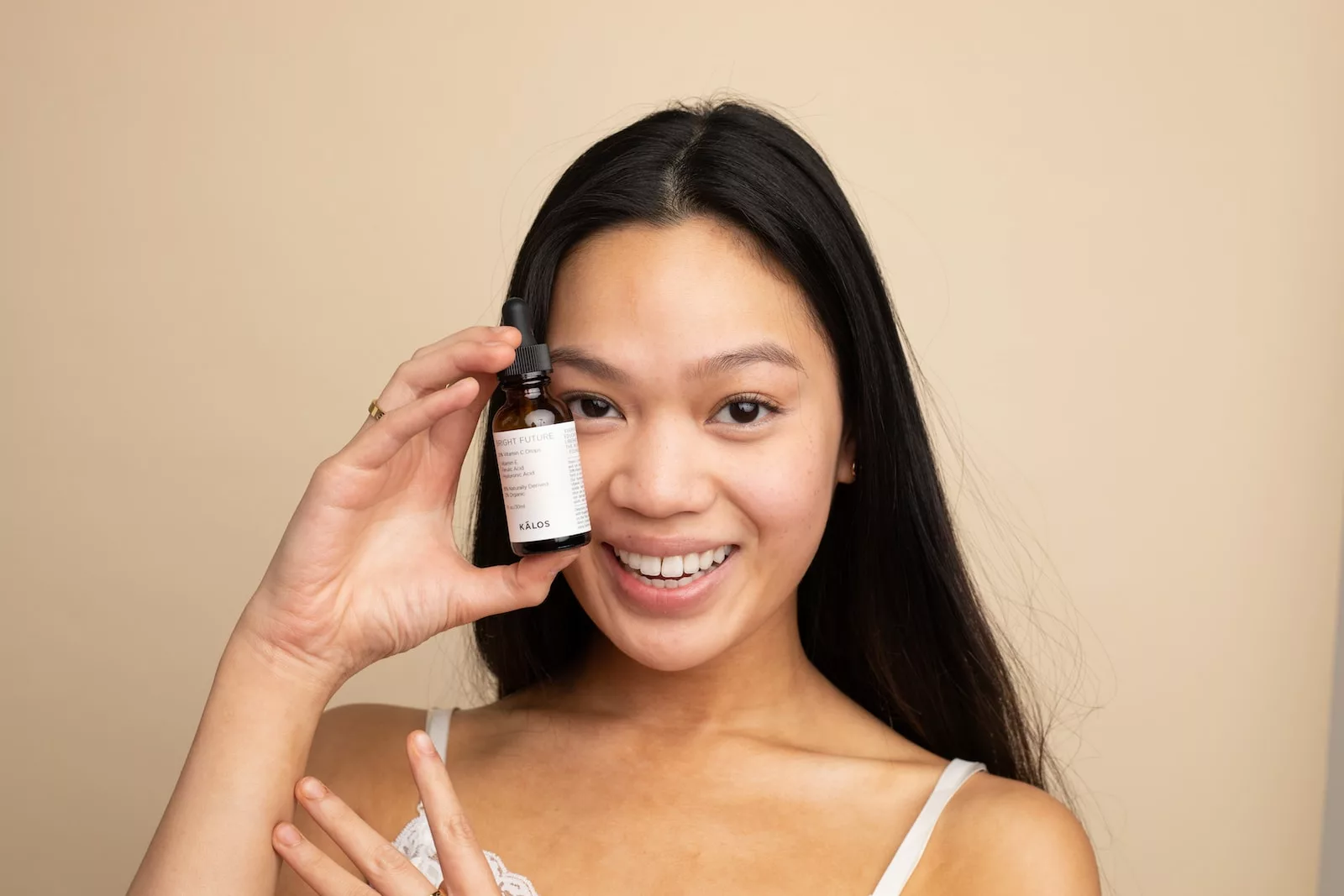 hyperpigmentation woman in white tank top holding white labeled bottle