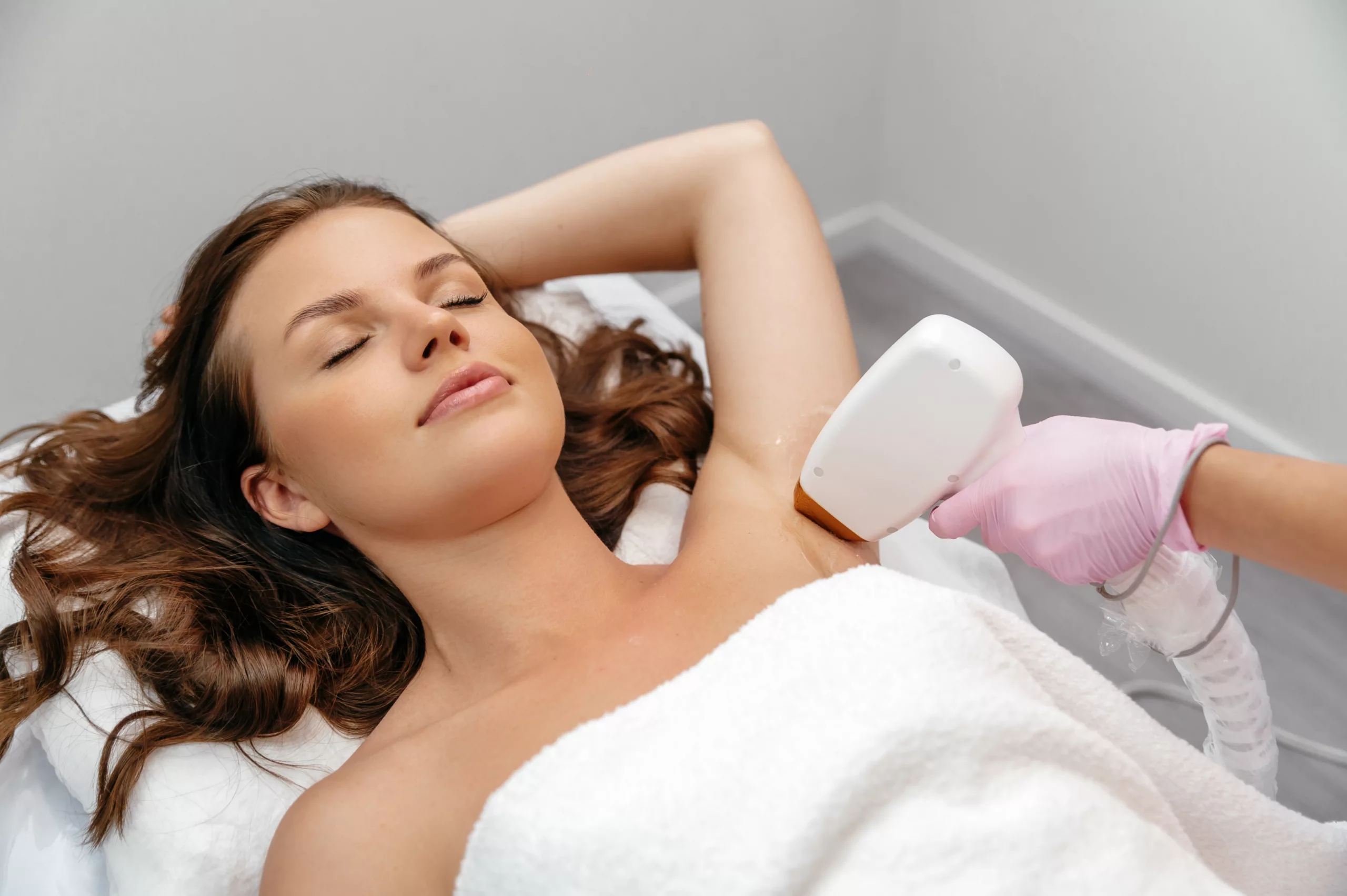 Beauty procedure. Hair removal by laser hair removal. Caucasian young woman lies on the couch with protective glasses during the procedure for removing unwanted hair with a laser machine